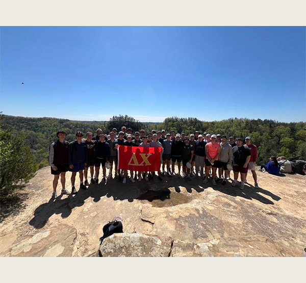 Members of the Delta Chi fraternity hold their fraternity flag at Red River Gorge, one of the sites for their mental health retreat.