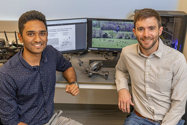 Gowtham Raj Veeraswamy Premkumar, M.S. ’24 and CEC assistant professor Bryan Van Scoy smile in front of computer screens displaying their research as well as a drone.