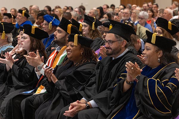 Doctoral candidates applaud during hooding ceremony