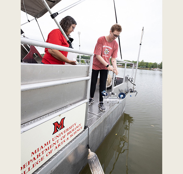 Lesley Knoll and a student collect samples from Acton Lake from a pontoon boat