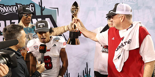 Miami University football Chuck Martin and musician and Arizona Bowl host Snoop Dogg hold the trophy following the RedHawks' victory.