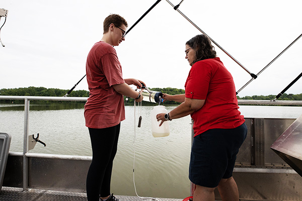 Lesley Knoll (right) and an undergraduate research student collect water samples from Acton Lake 