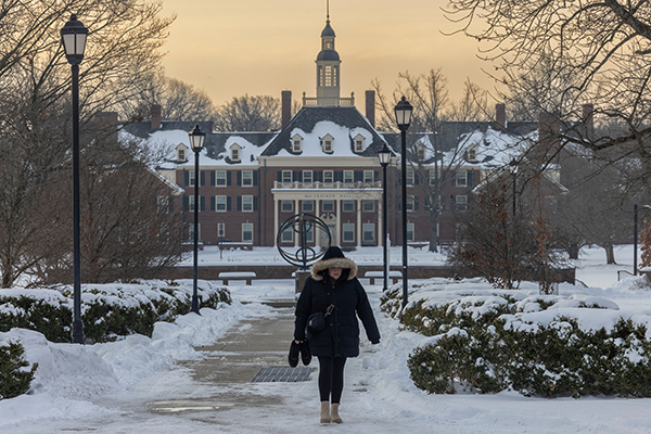 A person dressed in a warm coat walks past the Sundial on a cold day with lots of snow