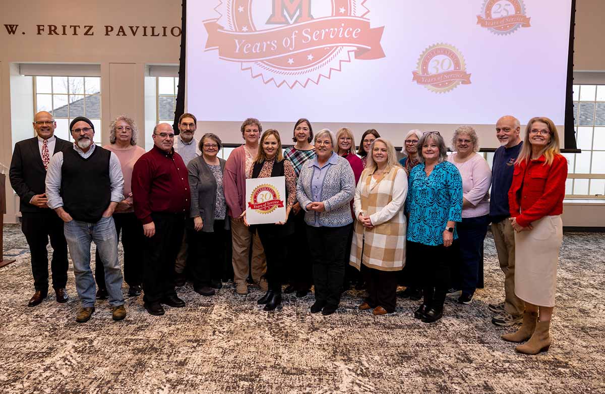 30 years of service group poses in front of screen