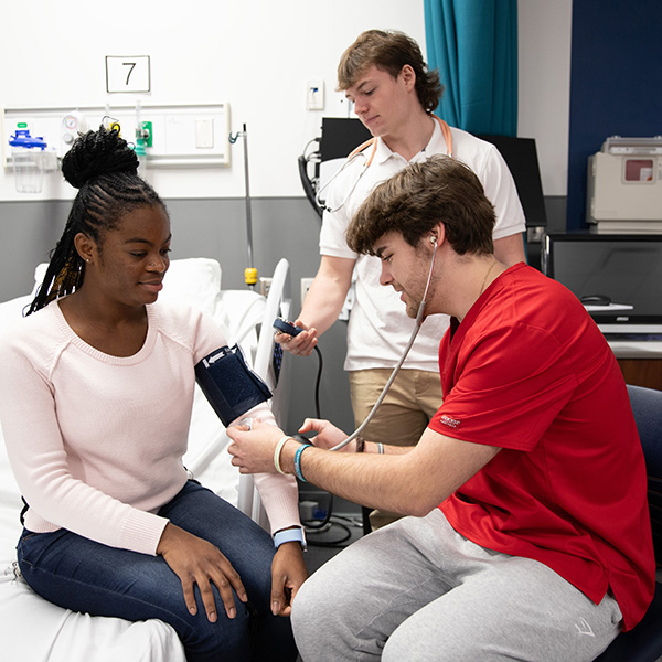 Osborne and Reed in the Nursing Lab as they demonstrate taking blood pressure on a fellow Nursing student